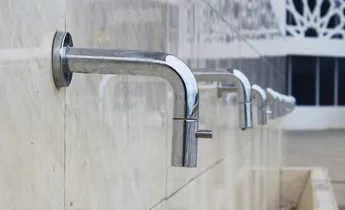 Row of stainless Steel Abution Taps on wall