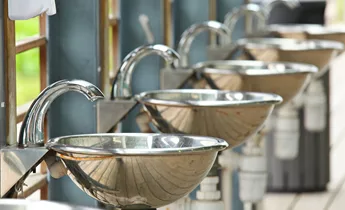 Row of stainless faucets/taps in a washroom