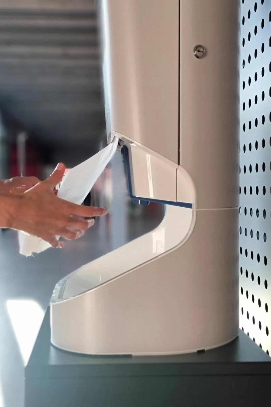 Hands receiving paper towel to dry from the Smixin handwash system
